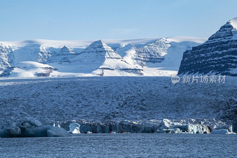 海神号(Poseidon Expeditions)探险游轮MV Sea Spirit(海神号Poseidon Expeditions)上的乘客乘坐Zodiac摩托化橡皮艇，在一个覆盖着积雪的山峰的大冰川附近巡航